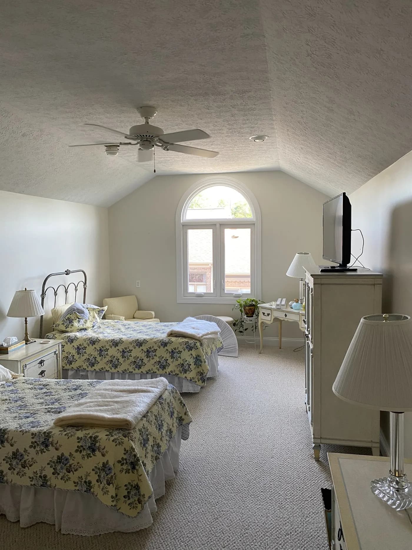 Bright bedroom with a vaulted ceiling and arched window