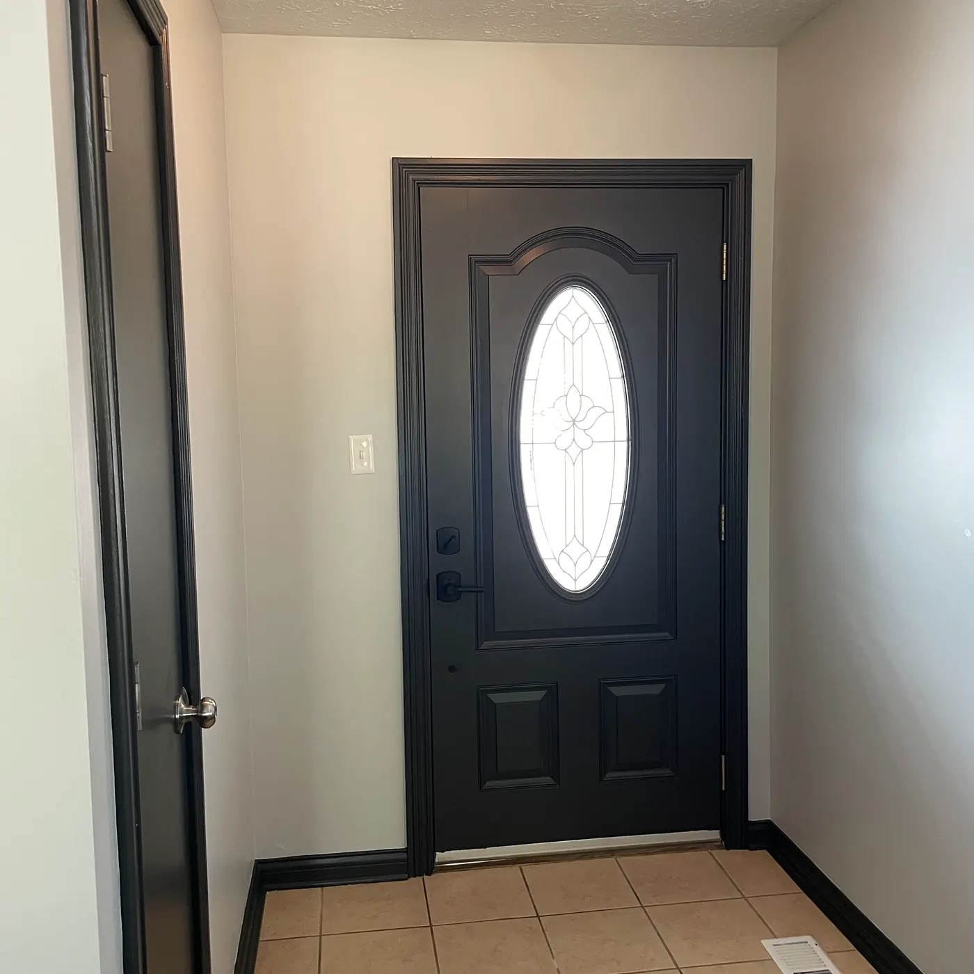 Front door with oval glass painted black from the inside