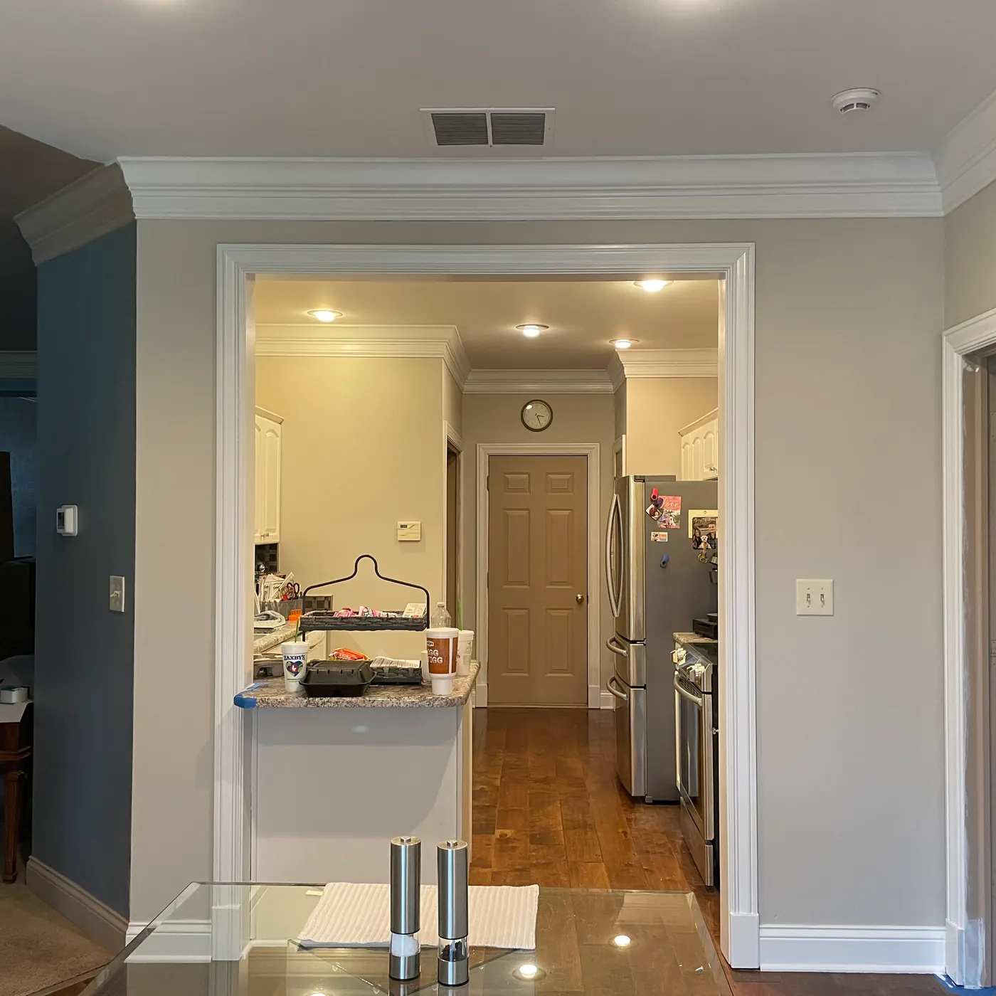 Hallway with fresh walls and white trim leading to the kitchen