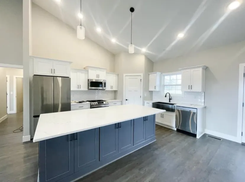 White kitchen cabinets with a blue island and vaulted ceiling