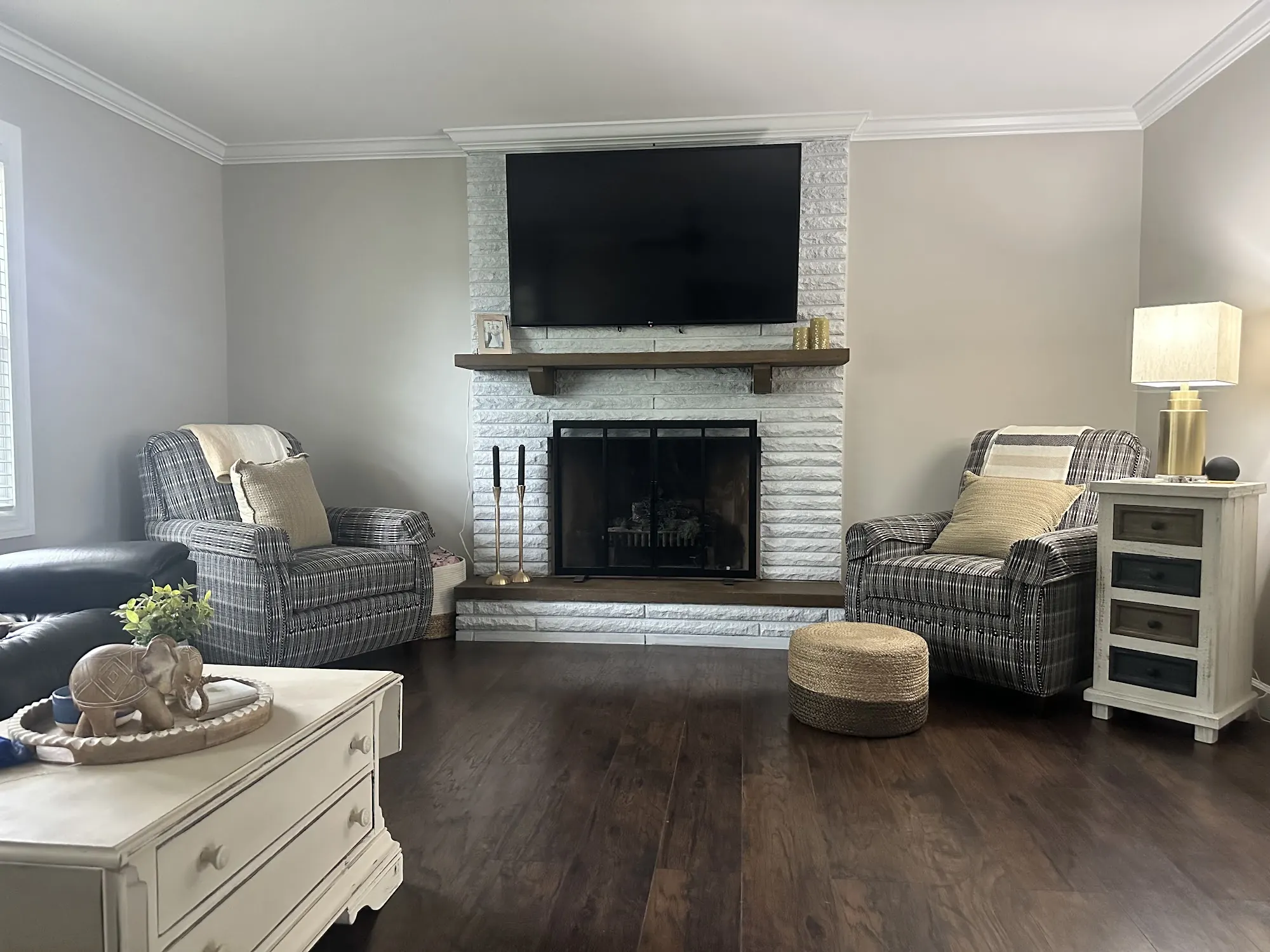 Living room with light gray walls and a painted white brick fireplace