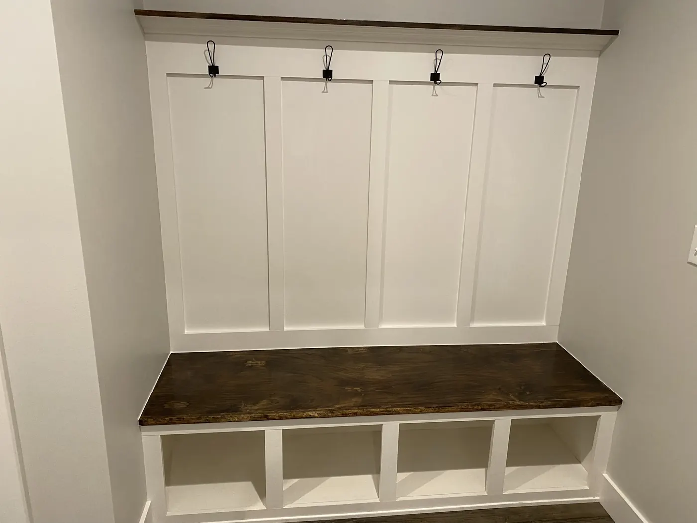 White board-and-batten mudroom bench with a stained wood seat