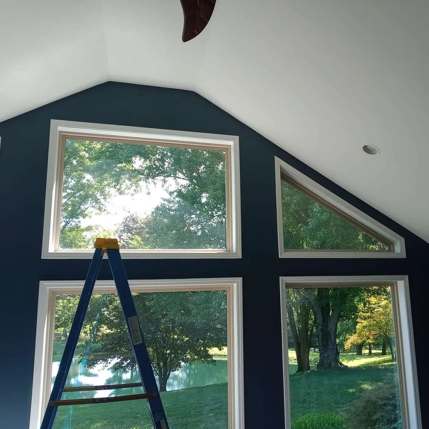 Navy accent wall around vaulted windows with a ladder in place
