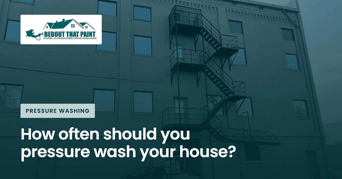 Blog title card with the Bebout That Paint logo and the title “How often should you pressure wash your house?” over a photo of pressure washing rig beside a four-story commercial building
